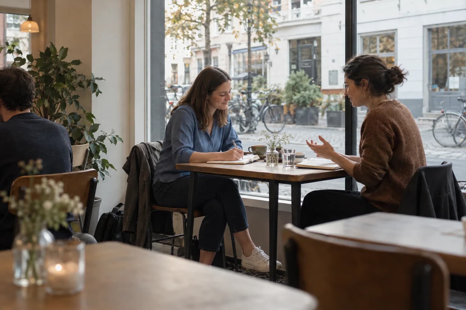 Two women talk over notebooks at a neighborhood café.
