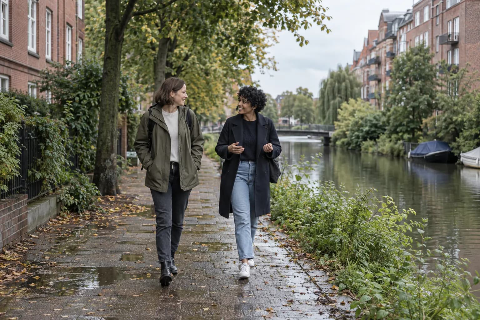 Two friends walk and talk along a leafy neighborhood canal.