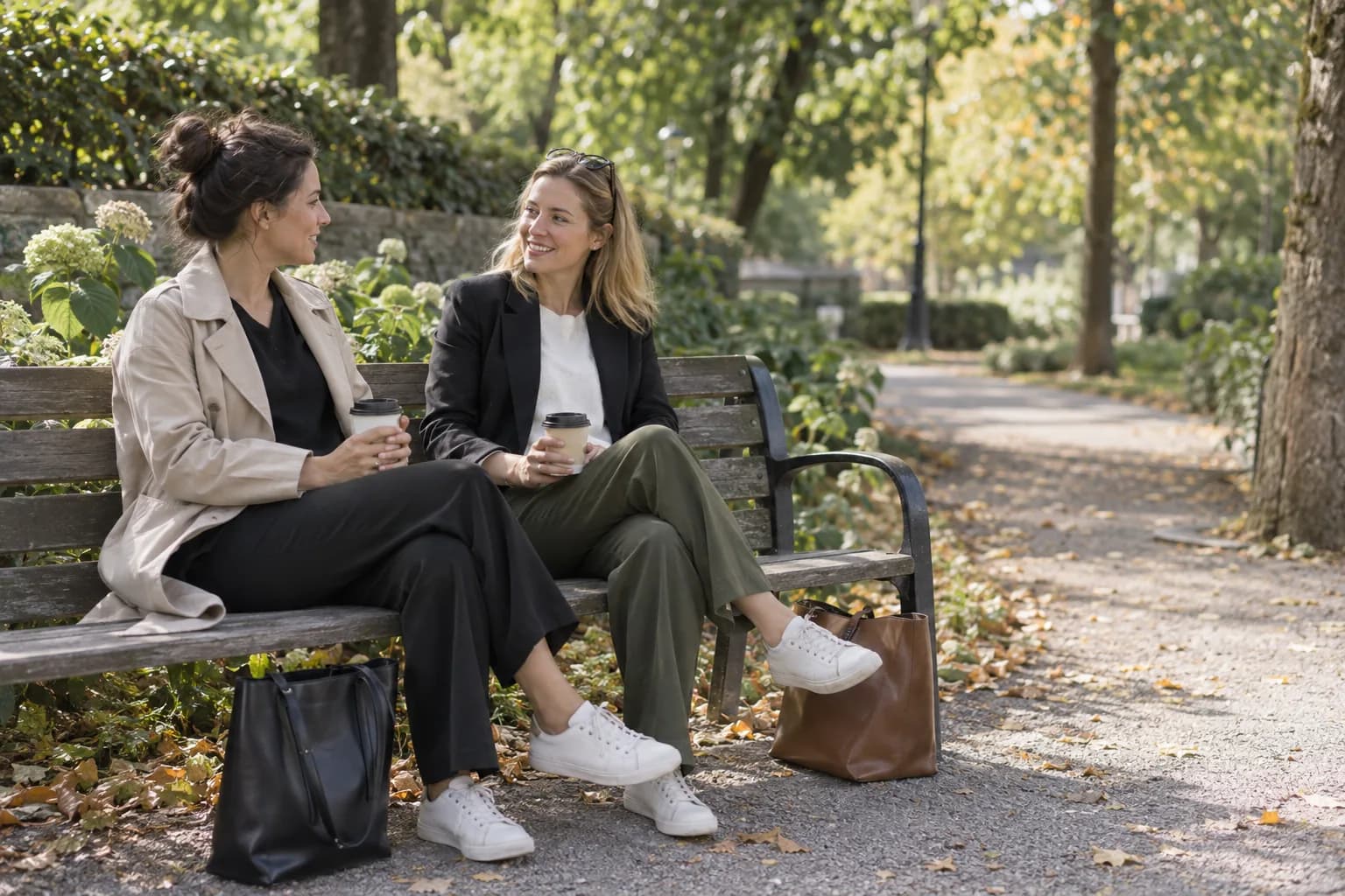 Two women talk on a park bench during a daytime walk.