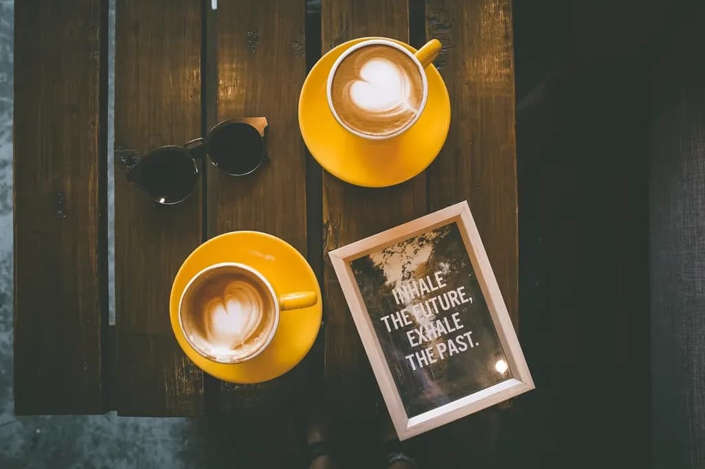Zwei Tassen Latte mit Mustern im Milchschaum stehen nebeneinander auf einem Tisch